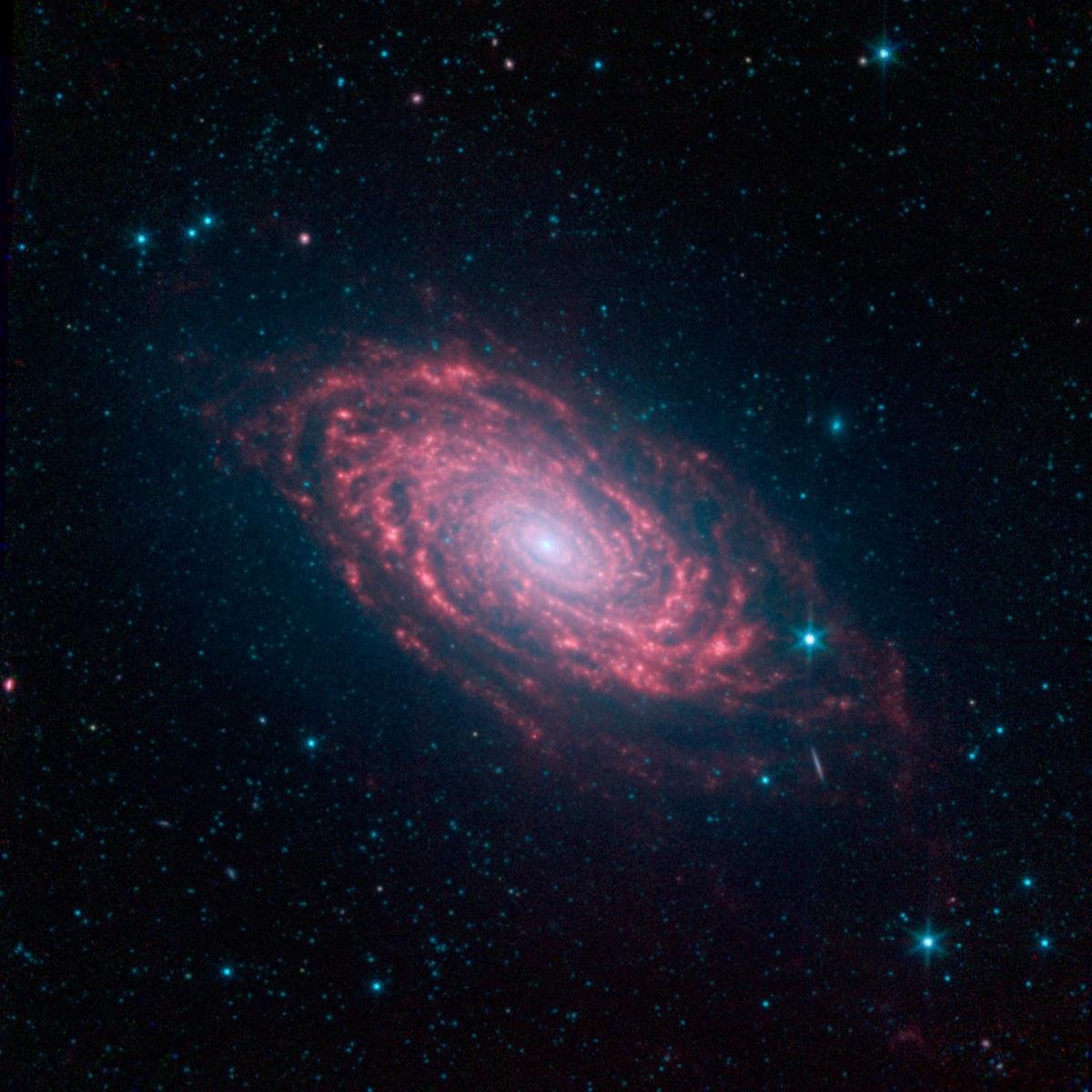 Galáxia espiral com braços avermelhados e centro brilhante, cercada de pontos de luz azulados sobre um fundo escuro